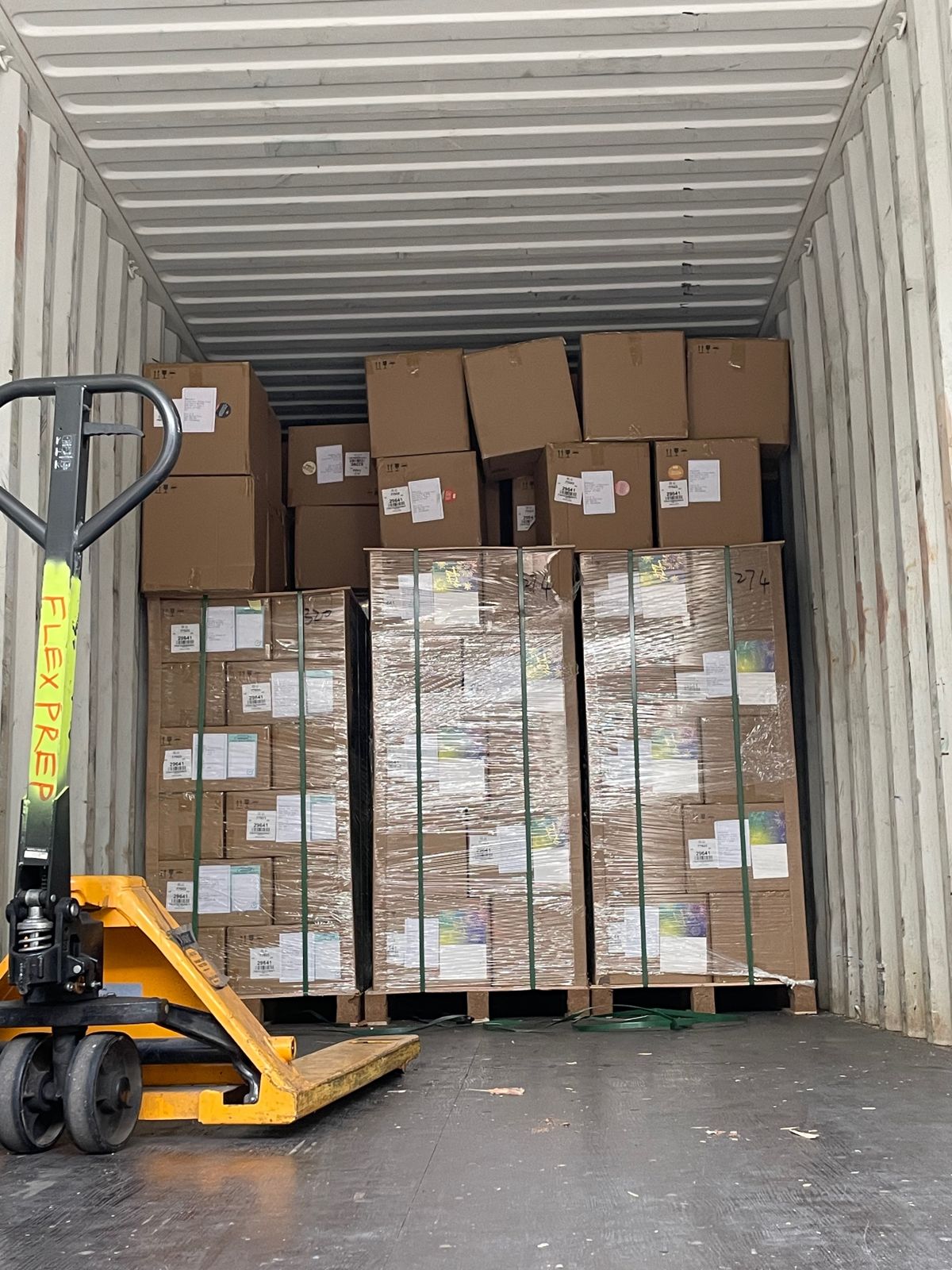 Pallet jack unloading palletized freight from a shipping container at FlexPrep